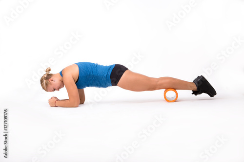 Fitness woman doing push ups in studio. Pretty woman using massage device isolated on white background. Health and fitness concepts.