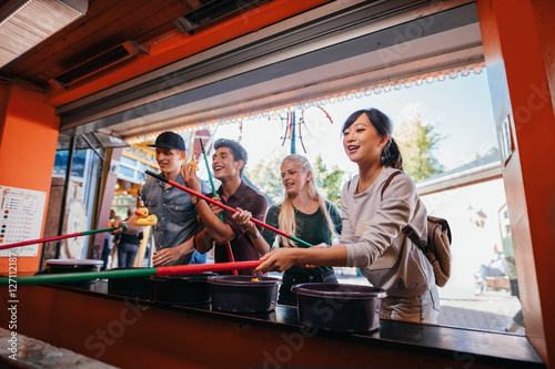 Multiracial friends playing arcade game at amusement park © Jacob Lund