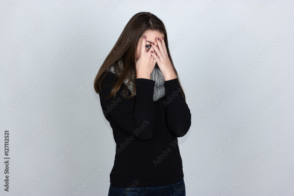 Portrait of a pretty woman in turtleneck sweater covering her eyes over gray background Portrait of a pretty woman in turtleneck sweater covering her eyes over gray background