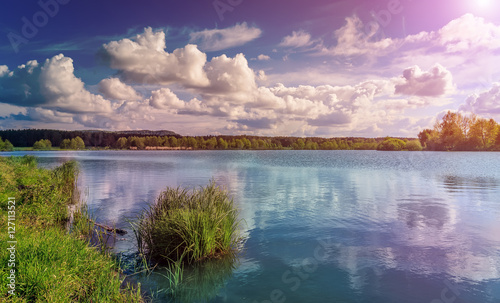 Grass and lake during sunset. Beautiful natural landscape. dramatic sky. Fantastic views of the Lake in the forest. under sunlight. Dramatic and picturesque scene. artistic images. beauty of the world