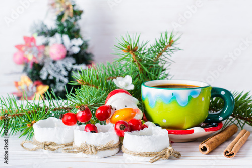 Новогодний натюрморт - чайные свечи, чашка кофе, еловые ветки, корица на фоне новогодней елки