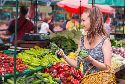 Young woman buying vegetables and fruits at local food market. photo