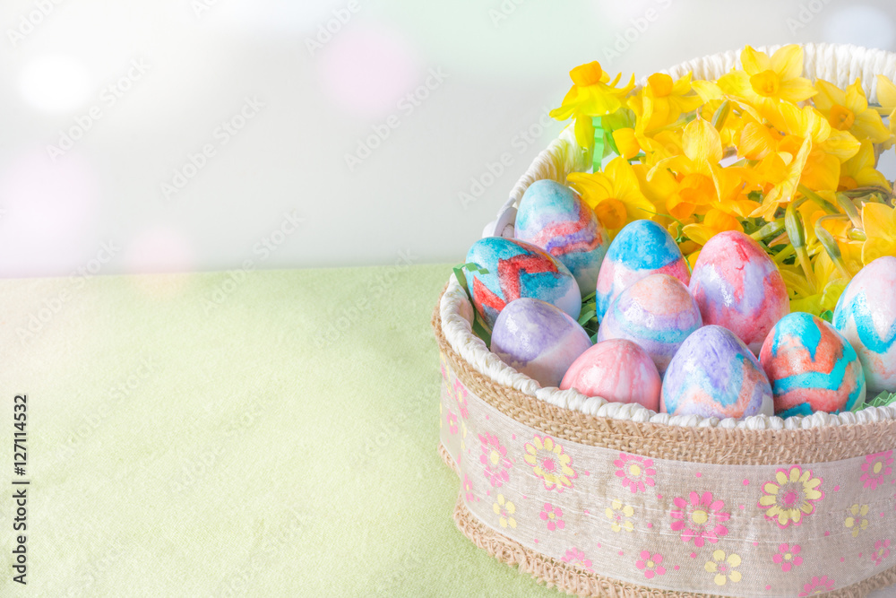 Fototapeta premium Basket of Hand Painted Easter Eggs with Daffodils on Table Horizontal with Copy Space Left & Bokeh