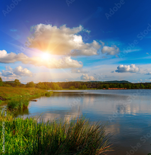 fantastic landscape. The dramatic scene sunset over a lake, rays erupt through the heavy storm clouds reflected in the water. color in nature.