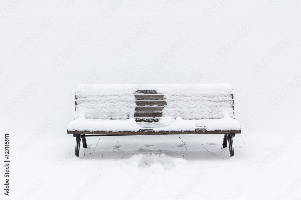 snow-covered wooden bench with an imprint of someone, who had been sitting in the middle; winter has gone
