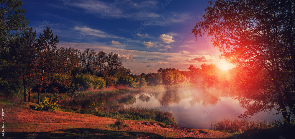 foggy sunrise over Lake in the spring forest. Fantastic  landscape over the river under Shining Sunlight. majestic picturesque sunset. Dramatic scenic summer scene. Instagram toning effect. 