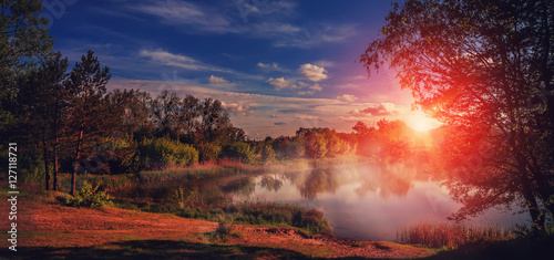 foggy sunrise over Lake in the spring forest. Fantastic  landscape over the river under Shining Sunlight. majestic picturesque sunset. Dramatic scenic summer scene. Instagram toning effect. 