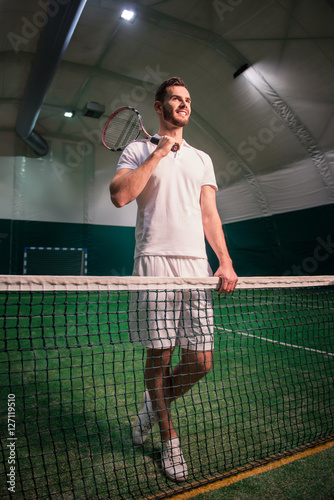 Cheerful professional tennis player training in indoor court