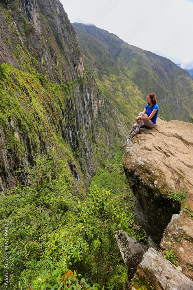 Young woman enjoying the view of Inca Bridge and cliff path near