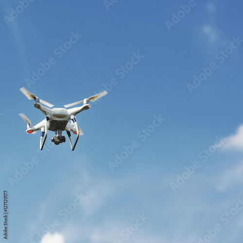 Fototapeta Naklejka Na Ścianę i Meble -  drone quad copter with digital camera flying hovering in the blue sky