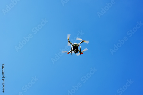 drone quad copter with digital camera flying hovering in the blue sky