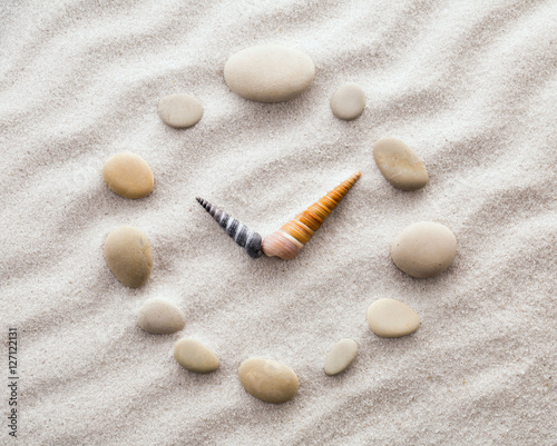 Stylized dial clock pebble and shells arrows on the sand for concentration and relaxation for harmony and balance in pure simplicity - macro lens shot