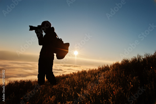 Silhouette of man photographer with camera on hand background mo