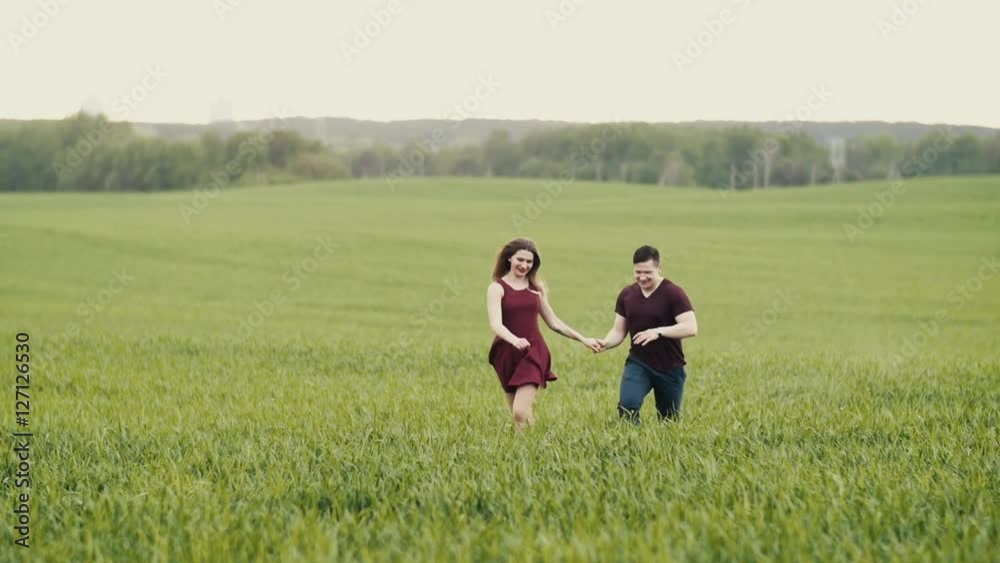 A couple in love running through a wheat field, holding hands, smiling, slow mo, steadicam shot A couple in love running through a wheat field, holding hands, smiling, slow mo, steadicam shot