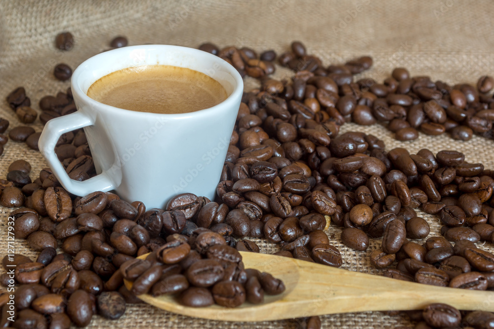 Cup and grain of coffee over textile background