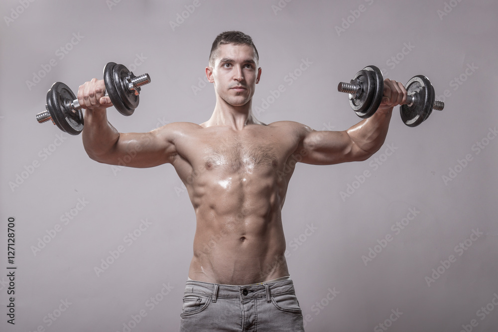 young man holding raised dumbbells