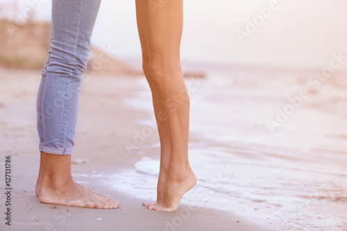 Male and female legs on seashore, closeup
