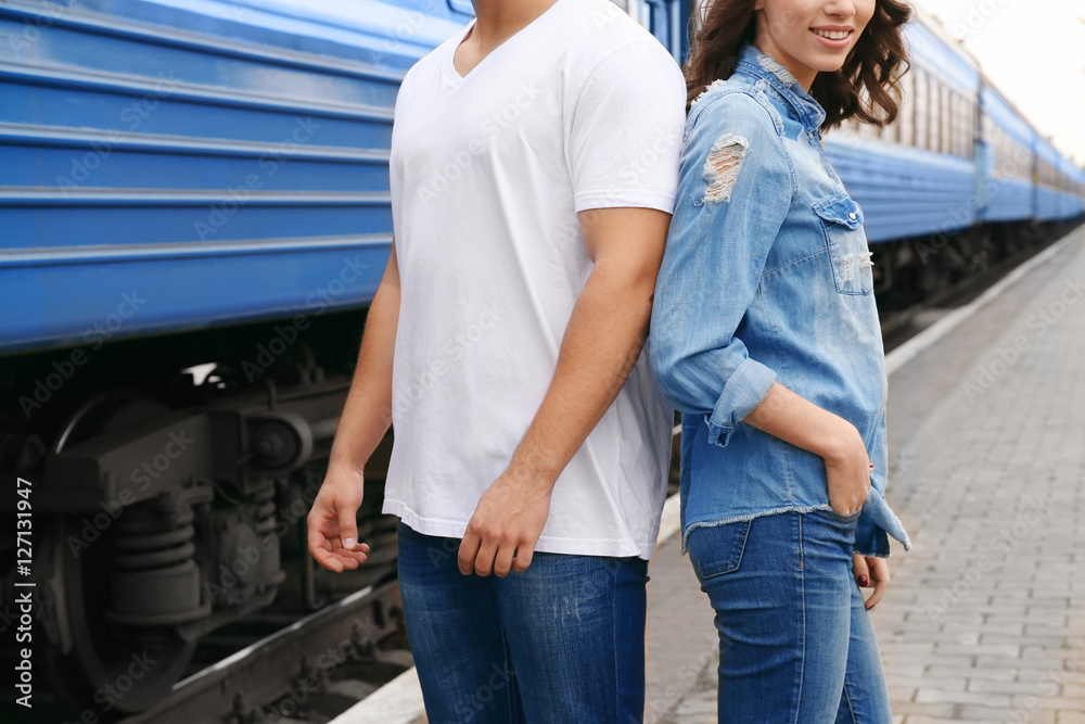 Young couple standing on railway platform near train, closeup