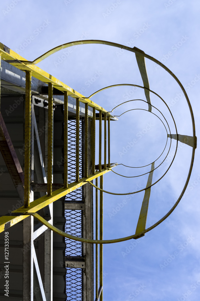 Naklejka premium Caged ladder leading up and blue sky