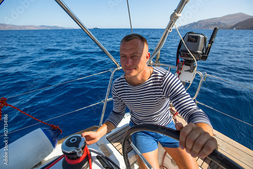 Young man at the helm of his yacht. © De Visu