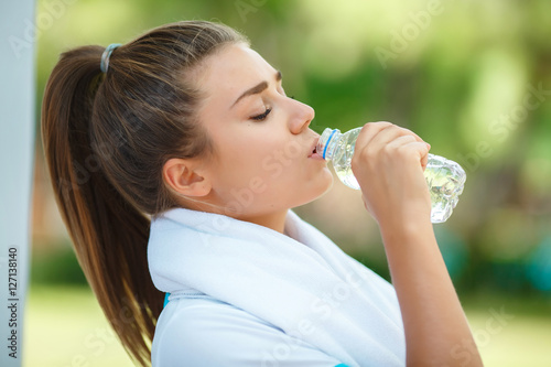 Fitness woman drinking water outdoors