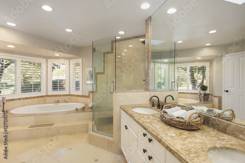 Luxury bathroom interior in marble with glass shower and oval bath tub and round shaped double sink.