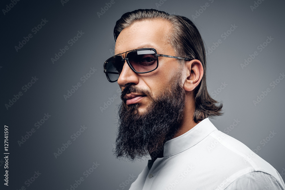 Fototapeta premium A man in sunglasses, dressed in white shirt on grey background.