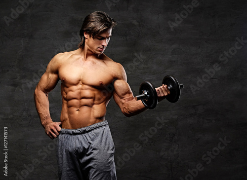 Shirtless muscular male holds dumbbell. © Fxquadro