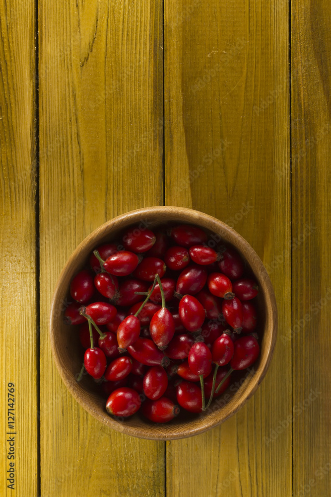 Ripe rosehips in wooden plate Ripe rosehips in wooden plate