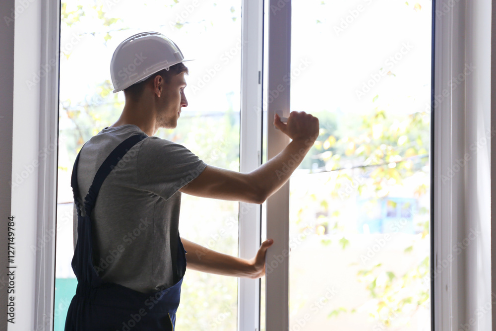 Construction worker installing window in house Construction worker installing window in house