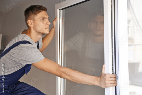 Construction worker installing window in house