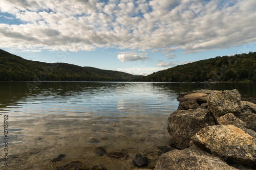 a mountain pond with sky reflection and rocks in the foreground in autumn in New England photo