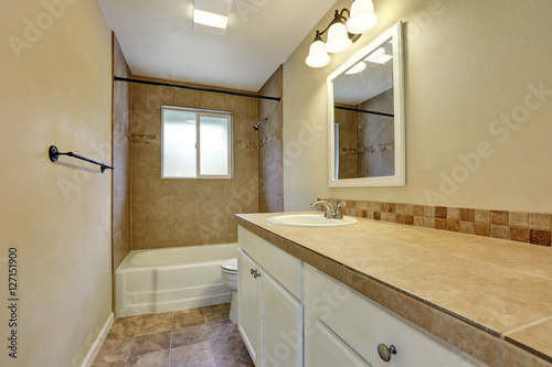 Interior design of beige bathroom with tile wall trim.