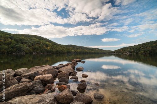 a mountain pond with sky reflection and rocks in the foreground in autumn in New England photo