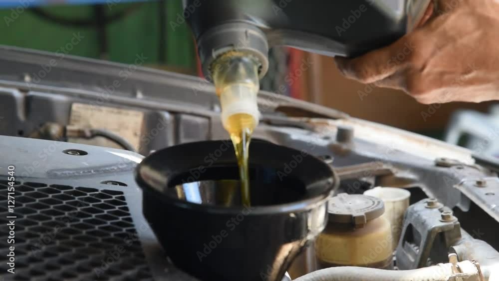 Car maintenance servicing mechanic pouring new oil lubricant into the car engine Car maintenance servicing mechanic pouring new oil lubricant into the car engine