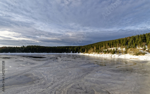 Frozen blue lake near forest