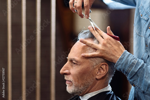 Old gentleman during haircut in barbershop