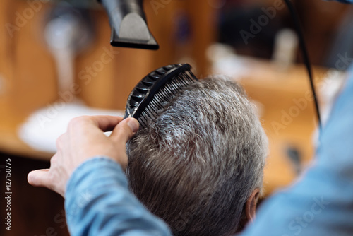 Close up of barber combing and blow drying