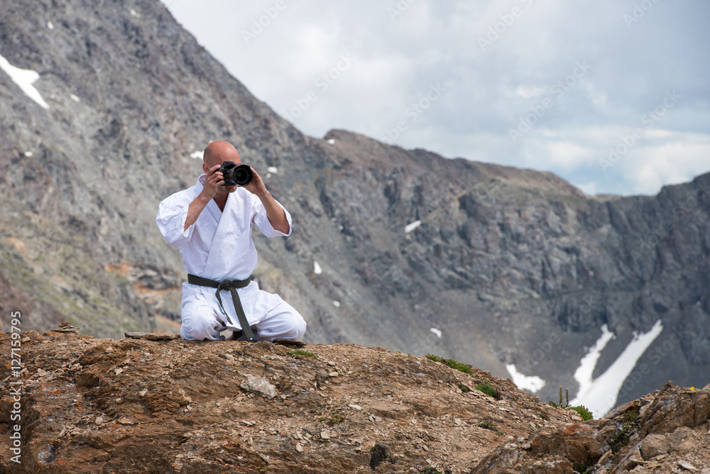 Fototapeta premium The man in a kimono sits in lotus position on top of mountain and taking pictures the camera.