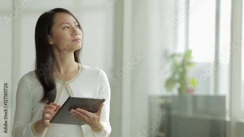MS SELECTIVE FOCUS Woman looks up from a digital tablet, thinking / Singapore