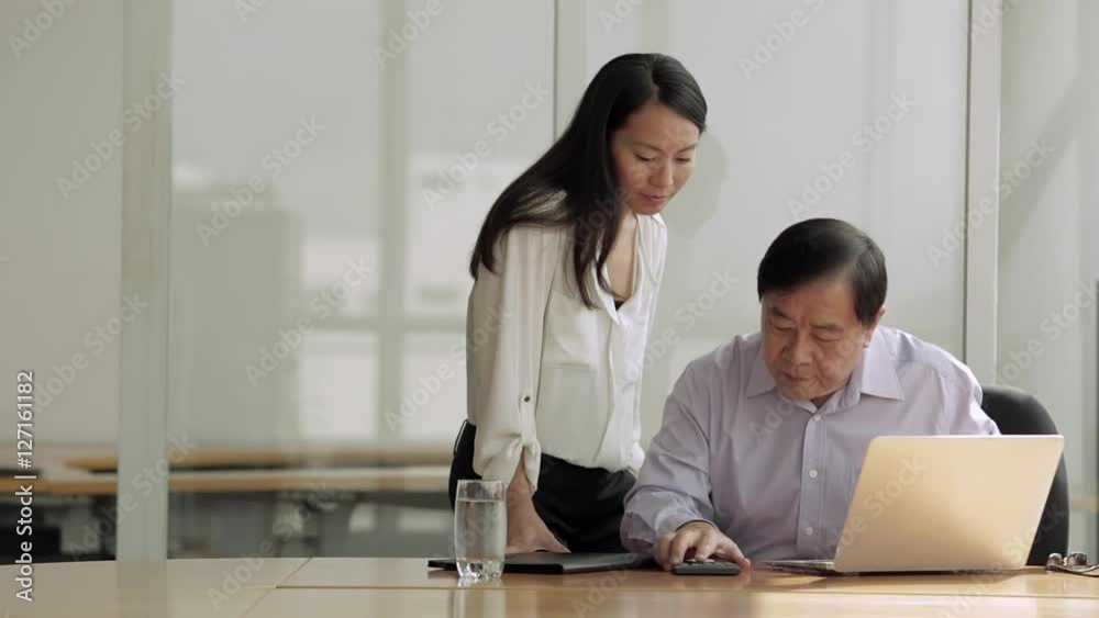 MS SELECTIVE FOCUS Senior businessman uses laptop while female colleague watches / Singapore MS SELECTIVE FOCUS Senior businessman uses laptop while female colleague watches / Singapore