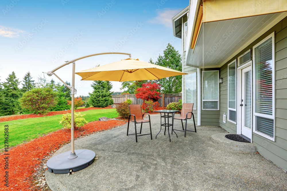 Concrete floor patio area with table, chairs and umbrella. Concrete floor patio area with table, chairs and umbrella.