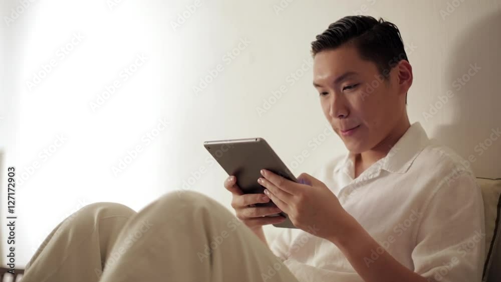 MS Mid-adult man using tablet pc on sofa / Singapore MS Mid-adult man using tablet pc on sofa / Singapore