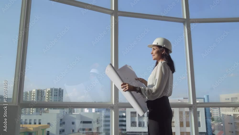 MS SELECTIVE FOCUS Female architect stands at window holding building plans / Singapore