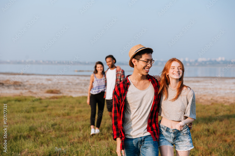 Two cheerful couples hugging and walking outdoors Two cheerful couples hugging and walking outdoors