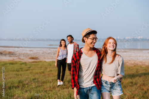 Two cheerful couples hugging and walking outdoors
