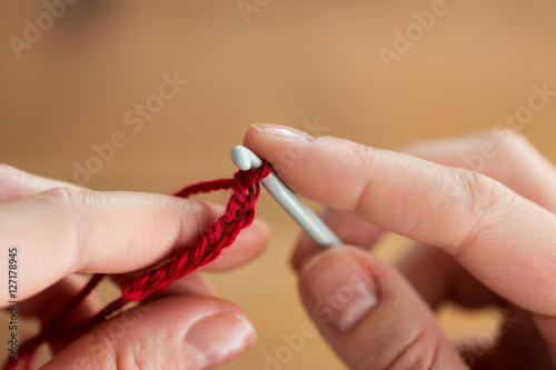 close up of hands knitting with crochet hook photo