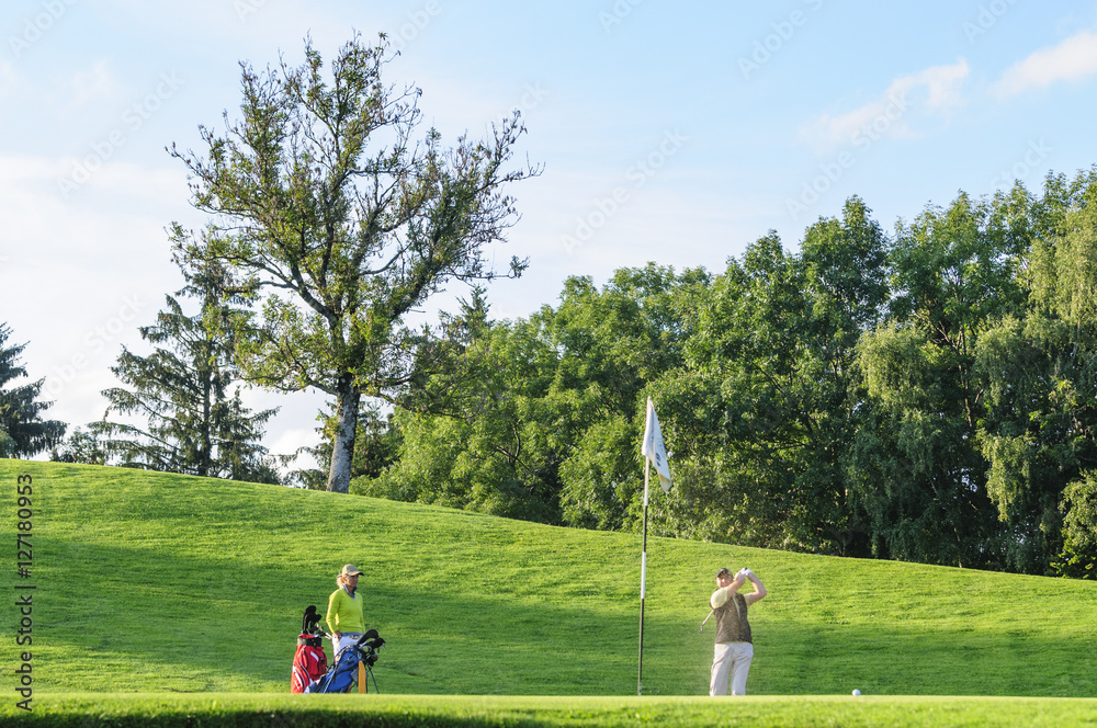 Golfer spielt einen Ball aus dem Bunker auf das Grün 