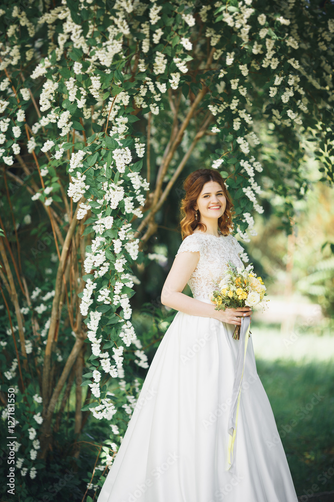 The bride holding bouquet of flowers in park. Wedding