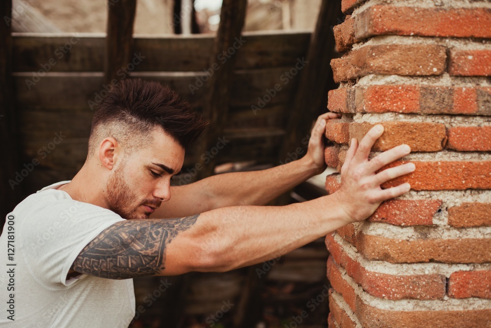 Fototapeta premium Attractive guy next to a brick wall
